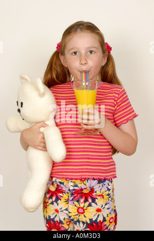 Girl holding teddy boire le jus d'orange avec de la paille Banque D'Images