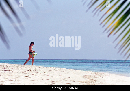 Une femme marche sur le rivage dans les Maldives Banque D'Images