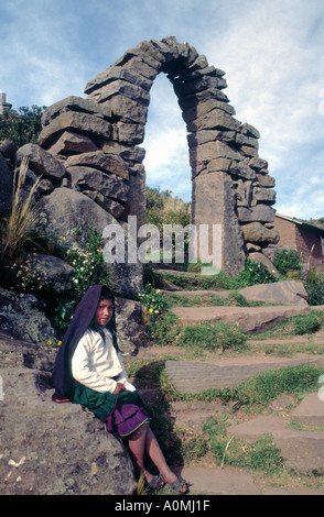 Jeune fille debout à côté d'une arche en pierre sur l'île de Taquile sur le lac Titicaca au Pérou Banque D'Images