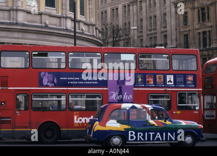 Londres, Angleterre, Royaume-Uni. London bus rouge et noir cab avec le mot 'Grande-bretagne' sur elle. Londres visible derrière les bâtiments. Banque D'Images