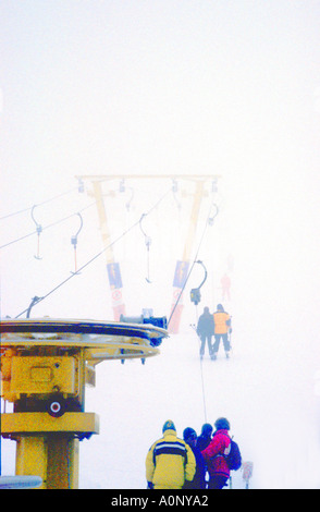 Treuil de levage de ski en premier plan avec des personnes s'évanouissant dans la brume qu'elle tire vers le haut Banque D'Images