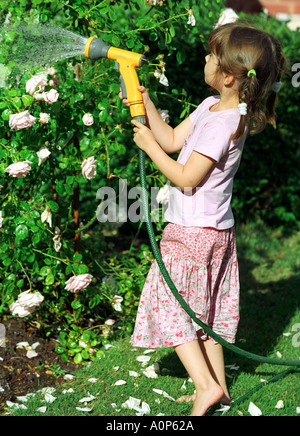 Les eaux d'une jeune fille avec des plantes et fleurs de l'eau d'un tuyau flexible Banque D'Images