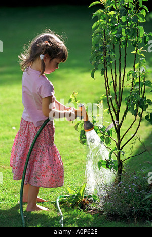 Les eaux d'une jeune fille avec des plantes et fleurs de l'eau d'un tuyau flexible Banque D'Images