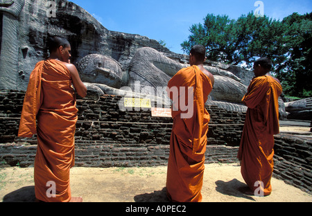 Trois moines en face d'une statue de Bouddha Gal Vihara à Polonnaruwa l'une des villes anciennes au Sri Lanka Banque D'Images