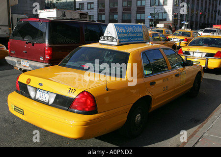 Un typique New York taxi jaune sous licence attend une voiture passagers sur le côté de la route street dans le centre-ville de New York USA Banque D'Images