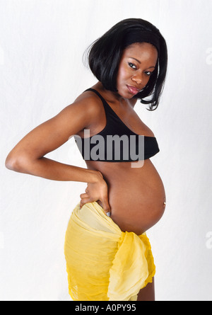 Femme noire enceinte dans un haut noir et jupe jaune Banque D'Images