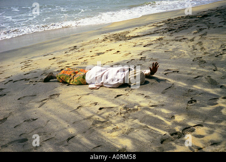 L'homme des populations autochtones dans des vêtements colorés se trouvant dans la plage par la mer couvrir avait la main de salut face à l'Asie du Sud Inde Varkala Kerala Banque D'Images