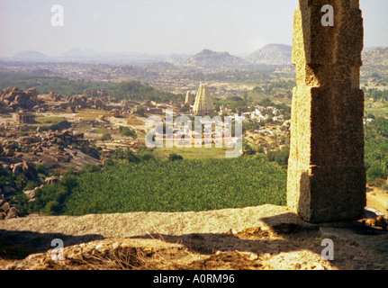 Vue panoramique sur la vieille ville ancienne ruines temple hindou vu à travers une porte en pierre colline verte Hampi Karnataka Inde Asie du Sud Banque D'Images