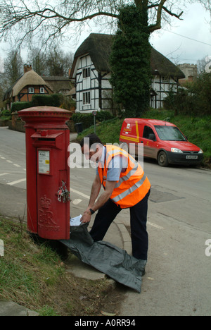 Vidange boîte à lettres facteur en zone rurale England UK Royal Mail postbox fort rouge Banque D'Images