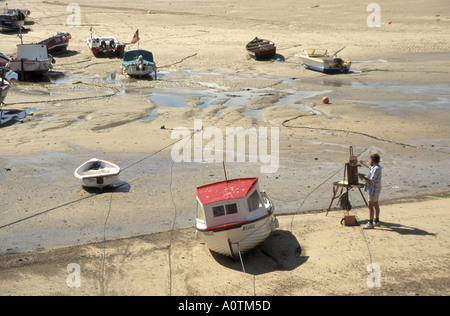 St Ives Harbour à marée basse avec l'artiste au travail sur plage de sable avec des bateaux amarrés Banque D'Images