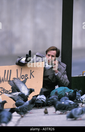 Photo humoristique d'un exécutif sans emploi dans la rue, entouré par les pigeons en maintenant un signe Banque D'Images