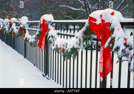 Arcs rouges et couvrir les lumières de Noël dans la neige le long d'une clôture Banque D'Images