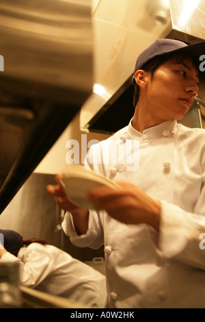 Close up of a waiter standing avec une serveuse se penchant derrière lui Banque D'Images