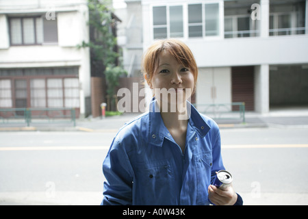 Portrait d'une femme auto mechanic holding une bière peut Banque D'Images