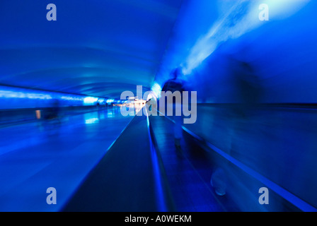 Quelques voyageurs sur trottoir roulant au cours de Spectacle son et lumière dans le tunnel entre les bornes à l'aéroport de Detroit au Michigan Banque D'Images