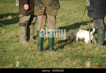 Les agriculteurs portant des bottes wellington debout dans un champ avec un chien. Banque D'Images