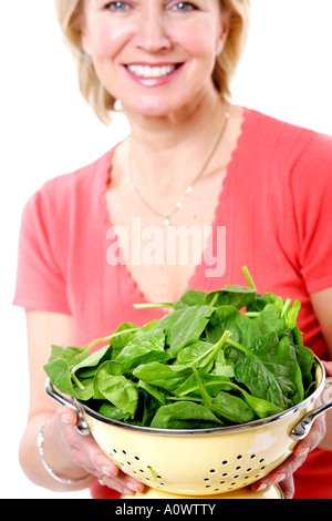 Mature Woman Holding passoire d'épinards Parution Modèle Banque D'Images