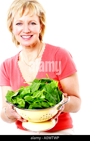 Mature Woman Holding passoire d'épinards Parution Modèle Banque D'Images