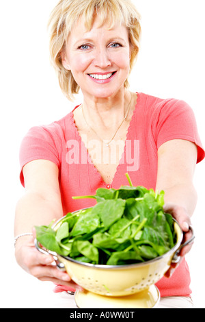 Mature Woman holding passoire d'épinards parution modèle Banque D'Images