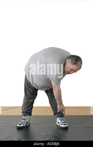 L'excès de mâle a un régiment de remise en forme pour perdre du poids et se mettre en forme. Ici il se penche et touche ses orteils. Banque D'Images