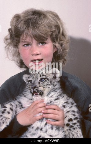 Megan Whittaker, 7 ans, avec un bonhomme de 8 semaines de léopard des neiges levé à la main, né au parc animalier de Port Lympne, Kent, Royaume-Uni Banque D'Images