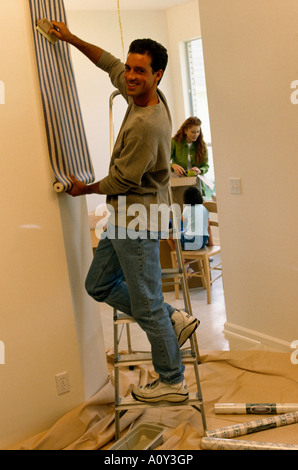 Young man putting up wallpaper Banque D'Images