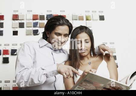 Close-up of a young couple le choix d'échantillons de tissus d'un magazine Banque D'Images