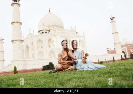 Jeune couple assis en face d'un mausolée, le Taj Mahal, Agra, Uttar Pradesh, Inde Banque D'Images