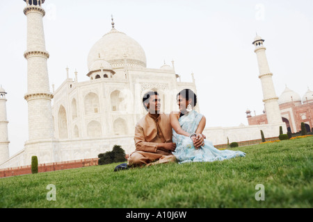 Jeune couple assis en face d'un mausolée, le Taj Mahal, Agra, Uttar Pradesh, Inde Banque D'Images