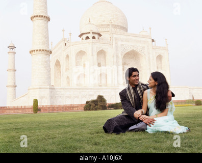 Jeune couple assis en face d'un mausolée, le Taj Mahal, Agra, Uttar Pradesh, Inde Banque D'Images