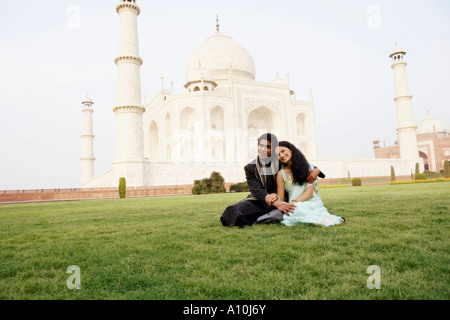 Jeune couple assis en face d'un mausolée, le Taj Mahal, Agra, Uttar Pradesh, Inde Banque D'Images