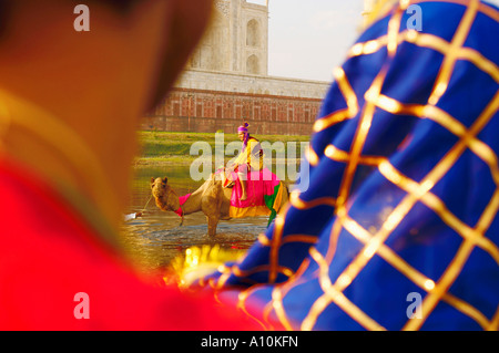 Vue arrière de deux personnes à la recherche d'un homme monté sur un chameau, Taj Mahal, Agra, Uttar Pradesh, Inde Banque D'Images