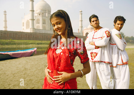 Portrait of a young woman smiling avec deux jeunes hommes debout derrière elle sur la rive, Taj Mahal, Agra, Uttar Pradesh, Inde Banque D'Images