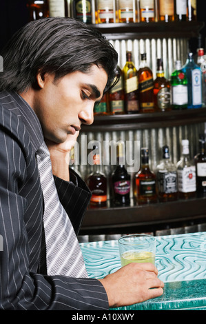 Portrait of a businessman holding a glass of whiskey à un comptoir bar Banque D'Images