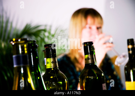 Femme de prendre un verre avec diverses bouteilles vides en vue Banque D'Images