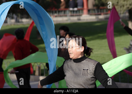 Femme à l'aide de bannières pour pratiquer le Tai Chi dans le parc du Temple du Ciel. Beijing, Chine. Banque D'Images