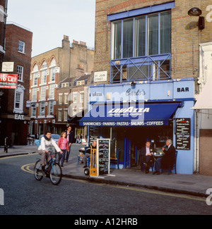 Woman riding son vélo passé Carlos bar café Lavazza à St John Street Clerkenwell Londres Angleterre Royaume-uni KATHY DEWITT Banque D'Images