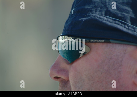 Un homme de couleur blanche portant des lunettes autour a une image d'une marina reflétée dans les verres Banque D'Images