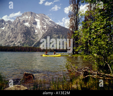 Deux jeunes canoéistes pagayer à travers un lac sous l'imposant sommet du mont Moran à Grand Teton National Park dans le Wyoming Banque D'Images