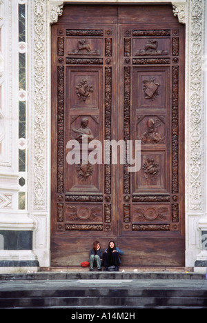 Deux personnes assis devant des portes gigantesques cathédrale Santa Croce dans Piazza Santa Croce Florence Italie Banque D'Images