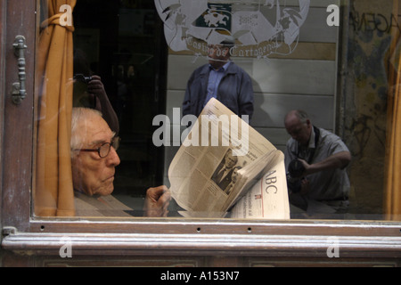 Un homme âgé qui lit des journaux et qui regarde la vie de la rue Dans un café espagnol Banque D'Images