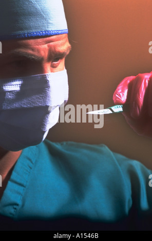 Un chirurgien de port de gants, vous y trouverez des gommages corporels et un masque tenant un scalpel Banque D'Images