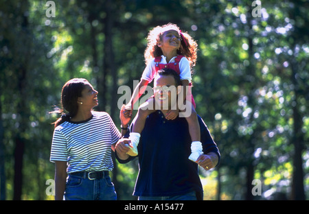 Un African American family walking in the park la fille monte sur les épaules de son père Banque D'Images