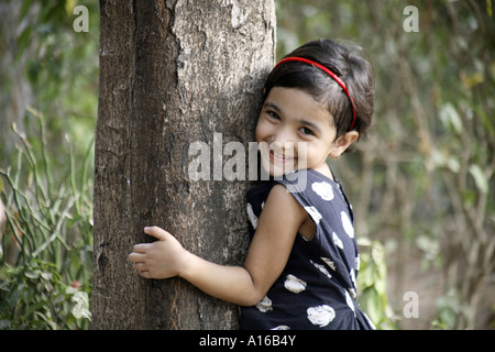 Jeune Indien little girl hugging a tree in Bombay Mumbai Inde Banque D'Images