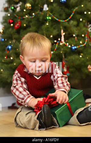 Garçon âgé d'un an opening Christmas present Banque D'Images