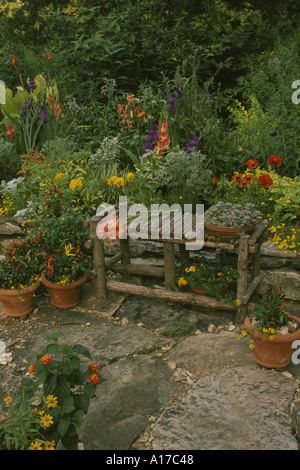 Banc en cèdre unique fait main accueil jardin fleuri avec des couleurs en fleurs orange gras par une paroi de rochers et le chemin, Midwest, USA Banque D'Images