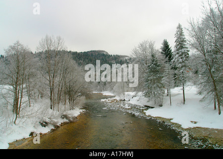 Une rivière serpente à travers le sol couvert de neige, Bled, Slovénie. Banque D'Images