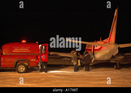 Un groupe de médecins du chargement d'un patient sur une civière à bord d'un avion lors d'une évacuation médicale d'urgence dans un village de l'Arctique Banque D'Images