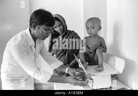 B/W d'un médecin pesant un enfant souffrant de malnutrition dans l'unité de nutrition des enfants, Dhaka, Bangladesh Banque D'Images