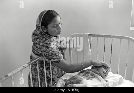 B/W d'une mère qui tend son enfant mal nourri dans l'unité de nutrition des enfants d'un hôpital de Dhaka, au Bangladesh Banque D'Images